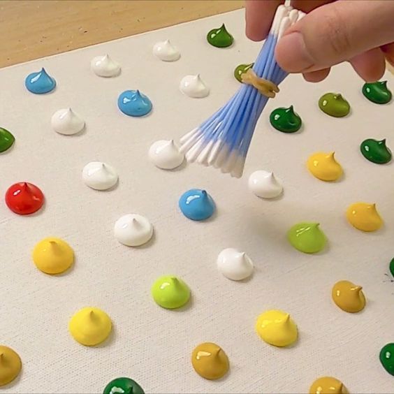 a person holding a paintbrush over some colorful candies