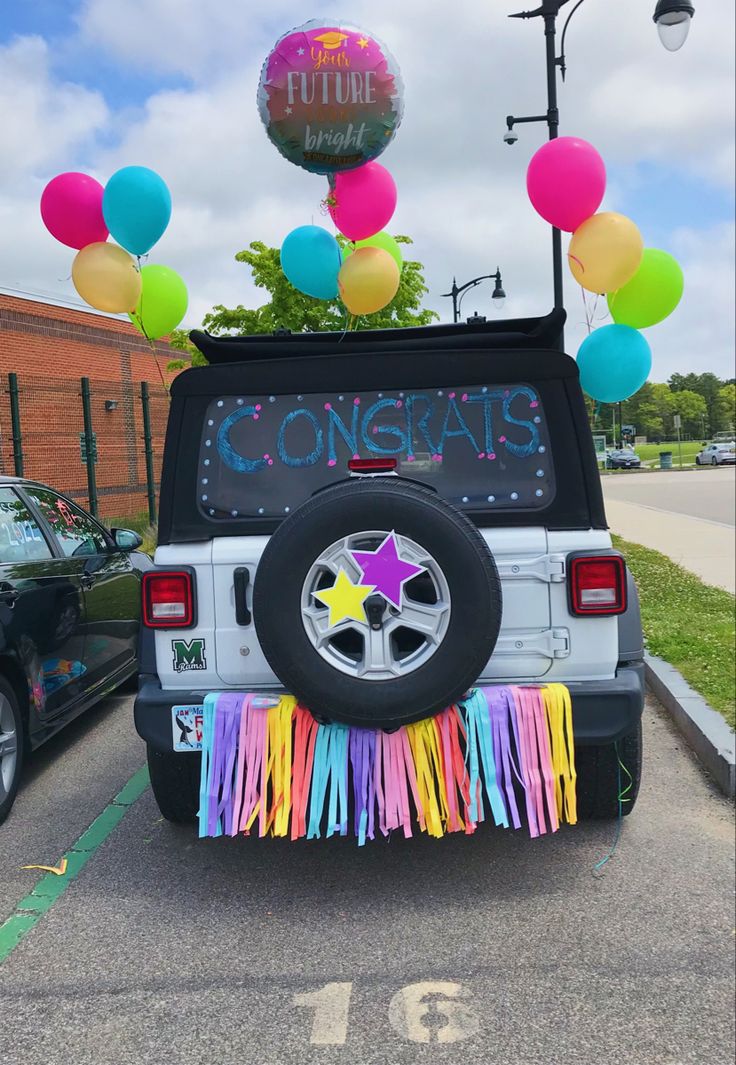 a jeep decorated with balloons, streamers and confetti is parked in the parking lot