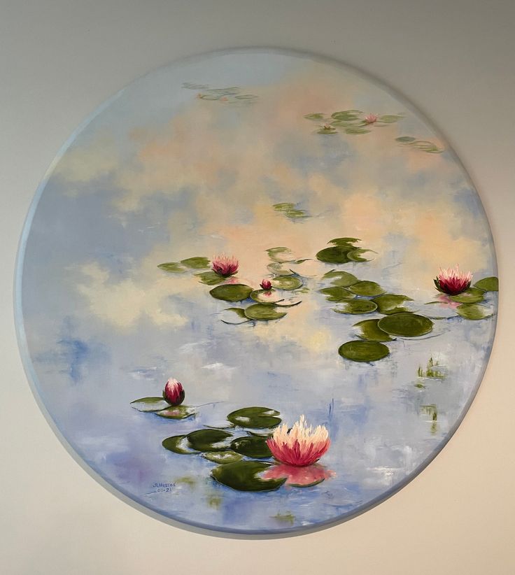 a round painting with water lilies floating on it's surface in a white walled room