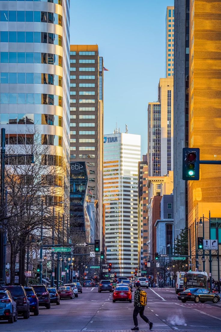 a city street filled with lots of tall buildings next to traffic lights and people walking on the sidewalk