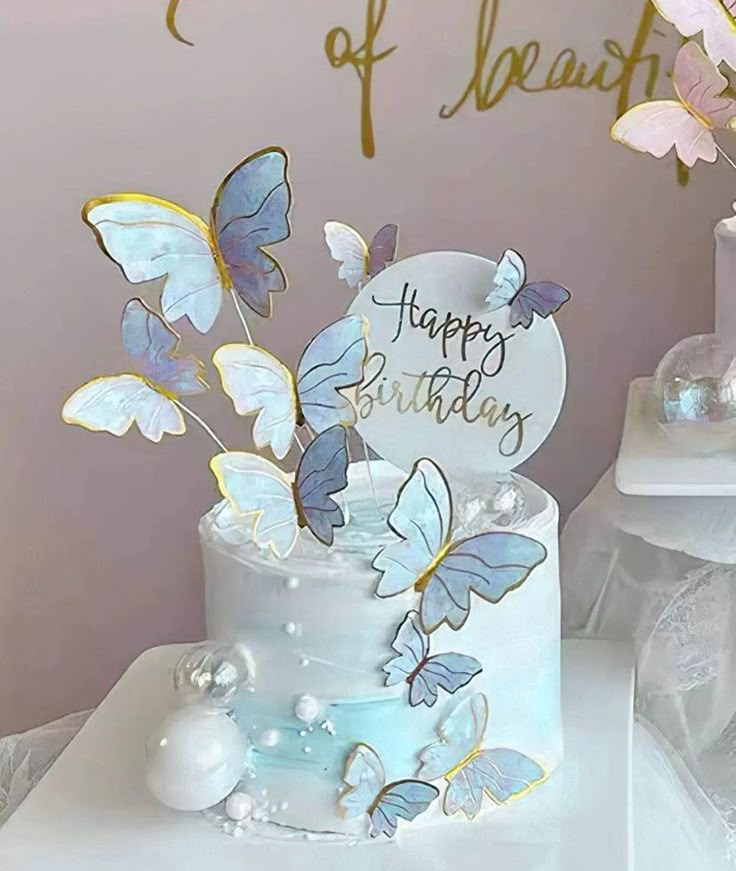 a white cake with blue butterflies on it and a happy birthday sign in the middle