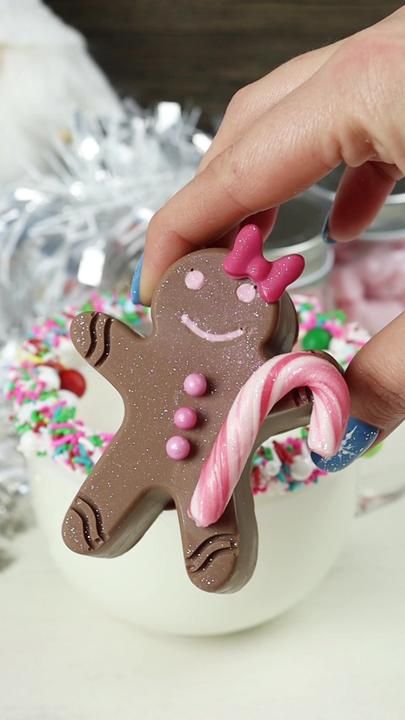 a hand holding a cookie shaped like a gingerbread with pink and green sprinkles