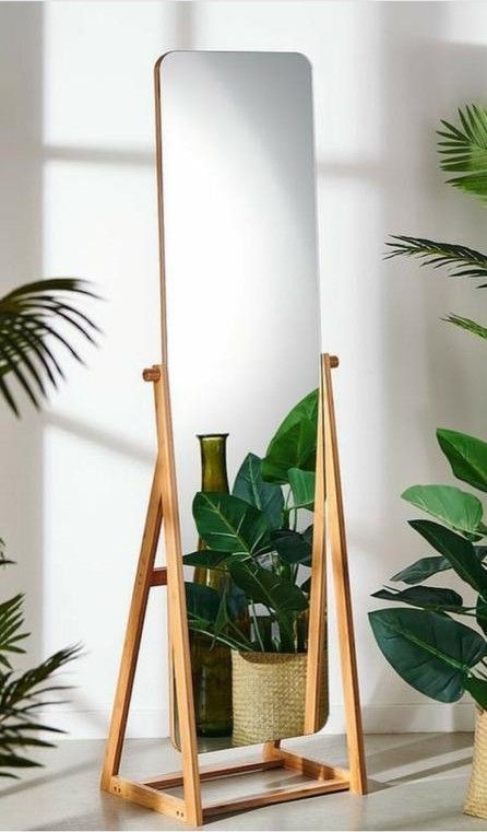 a mirror sitting on top of a wooden stand next to a potted green plant