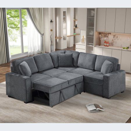 a living room with a sectional couch and bookcases on the floor in front of a window