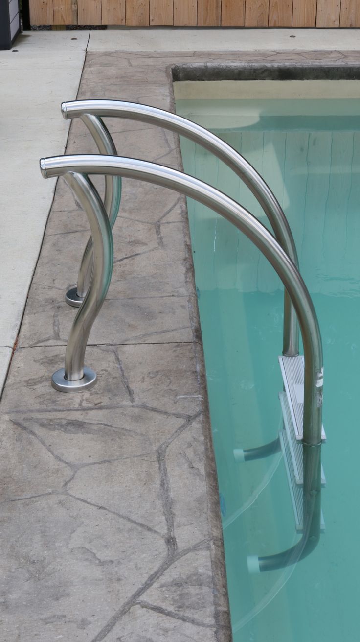 an empty swimming pool with metal railings on the edge and water in the middle