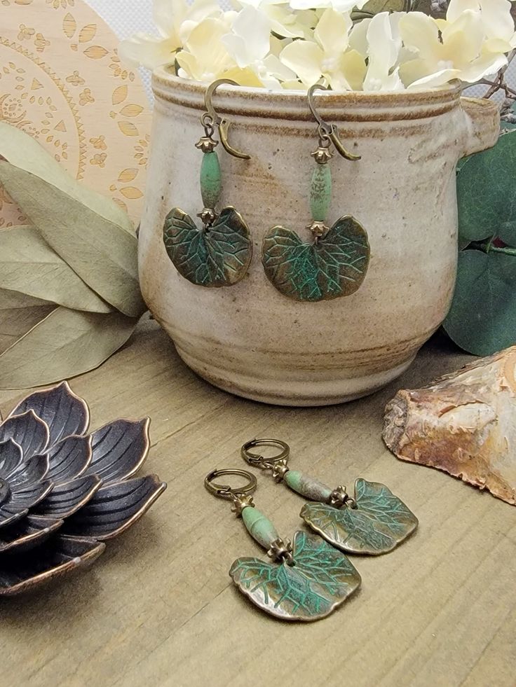 Wear a piece of botanical beauty with these amazing earrings! Antiqued brass ginkgo leaves with a touch of green verdigris will make a statement and delight your friends. Magnesite beads and brass accents will take them over the top and make them the star of any outfit. Antiqued brass verdigris leaf charms Magnesite elongated beads Brass accents Lever back ear closures Drop Length 2" Created in studio - Wilmington, NC Artisan Green Brass Earrings, Vintage Green Patina Earrings, Bohemian Leaf-shaped Brass Jewelry, Bohemian Brass Leaf Jewelry, Nature-inspired Leaf Shaped Brass Jewelry, Nature-inspired Leaf-shaped Brass Jewelry, Green Brass Earrings Nature-inspired, Green Bohemian Earrings With Patina, Green Patina Bohemian Earrings