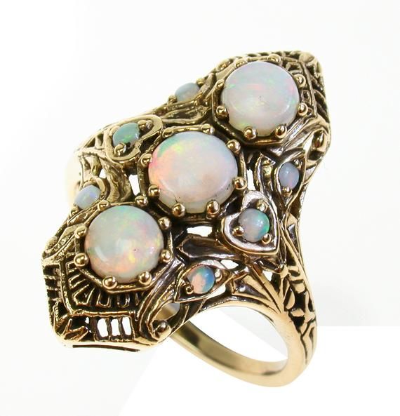 BEAUTIFUL 9CT/9K SOLID GOLD & OBLONG NATURAL OPAL VINTAGE RINGThis STUNNING Vintage Inspired ring has been majestically crafted from 9ct Solid Yellow Gold. Three claw set Round Cut NATURAL Opals brings this ring to life along with six accentuating NATURAL Opals claw set on each side of the ring. The entire face has a detailed filigree pattern including flowers engraved on the shoulders adding additional appeal to this exquisitely feminine ring. Surrounding the face of this GORGEOUS ring are Gold Opal Ring In 14k, Unique Gold Opal Ring In 14k, Antique Gold Opal Ring With Multi-stones, Antique Gold Multi-stone Opal Ring, Unique Multi-stone Opal Ring In Gold, Unique Gold Opal Ring With Multi-stone, Yellow Gold Multi-stone Art Deco Jewelry, Collectible Opal Ring In 14k Gold, Art Deco Multi-stone Yellow Gold Jewelry