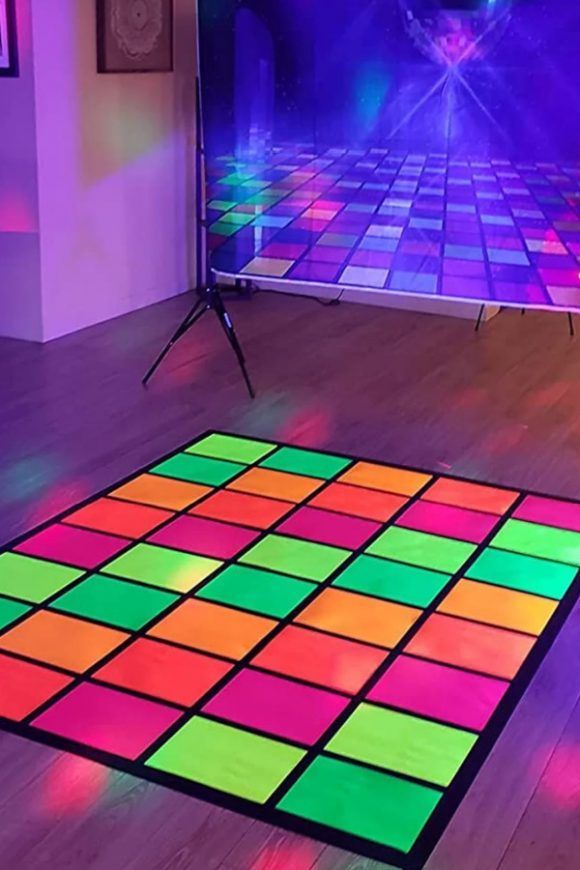 a colorful dance floor is shown in front of two televisions with bright lights on them