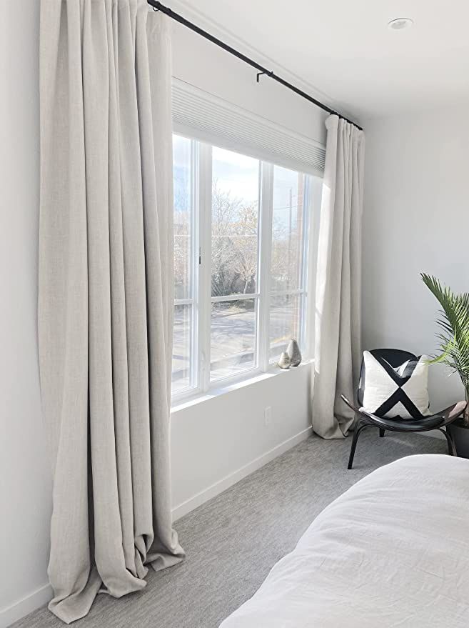 a bedroom with a bed, chair and large window overlooking the street in front of it