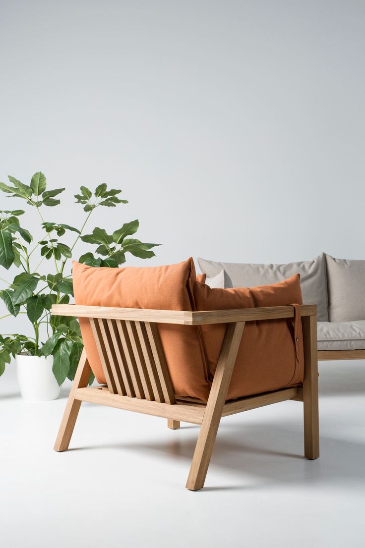 a wooden chair sitting next to a potted plant on top of a white floor