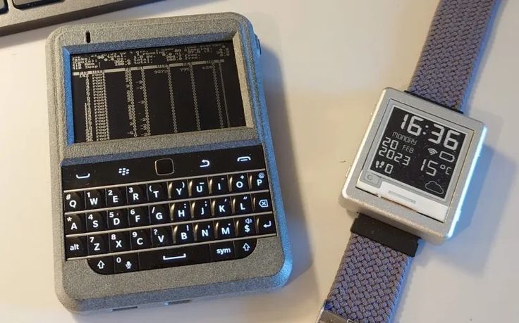 a smart phone sitting on top of a table next to an electronic device with a wrist strap