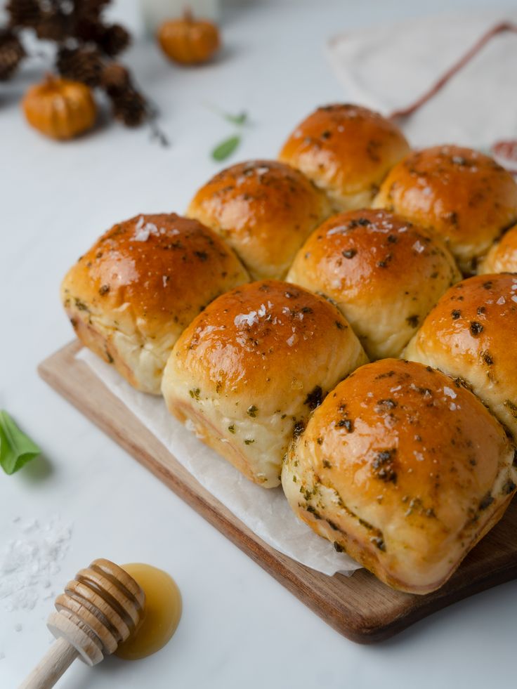 several rolls on a cutting board with butter and herbs