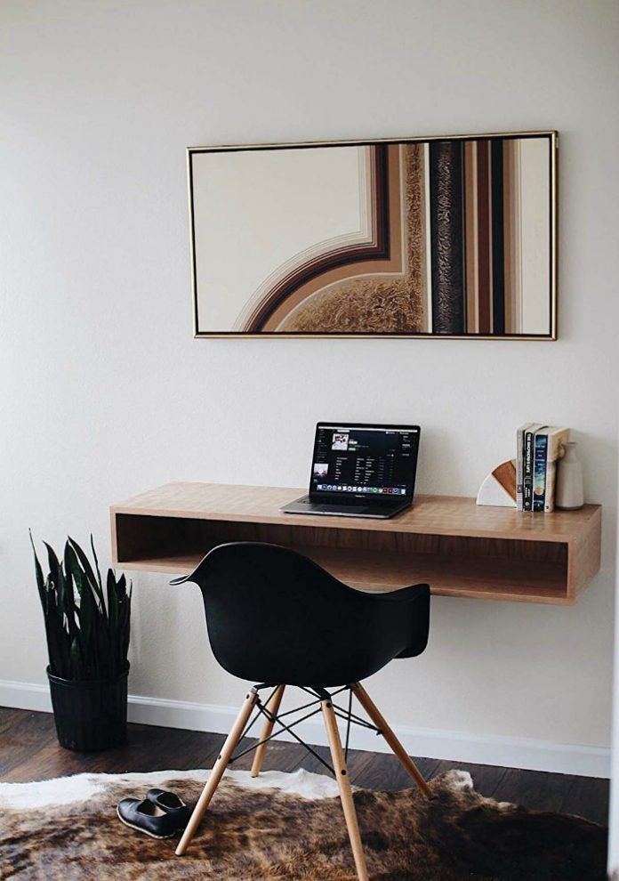 a laptop computer sitting on top of a wooden desk next to a chair and potted plant