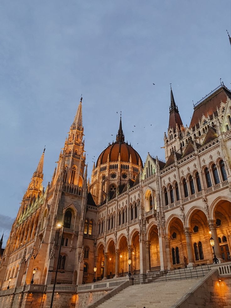 an ornate building with many spires lit up in the evening time, along with steps leading to it