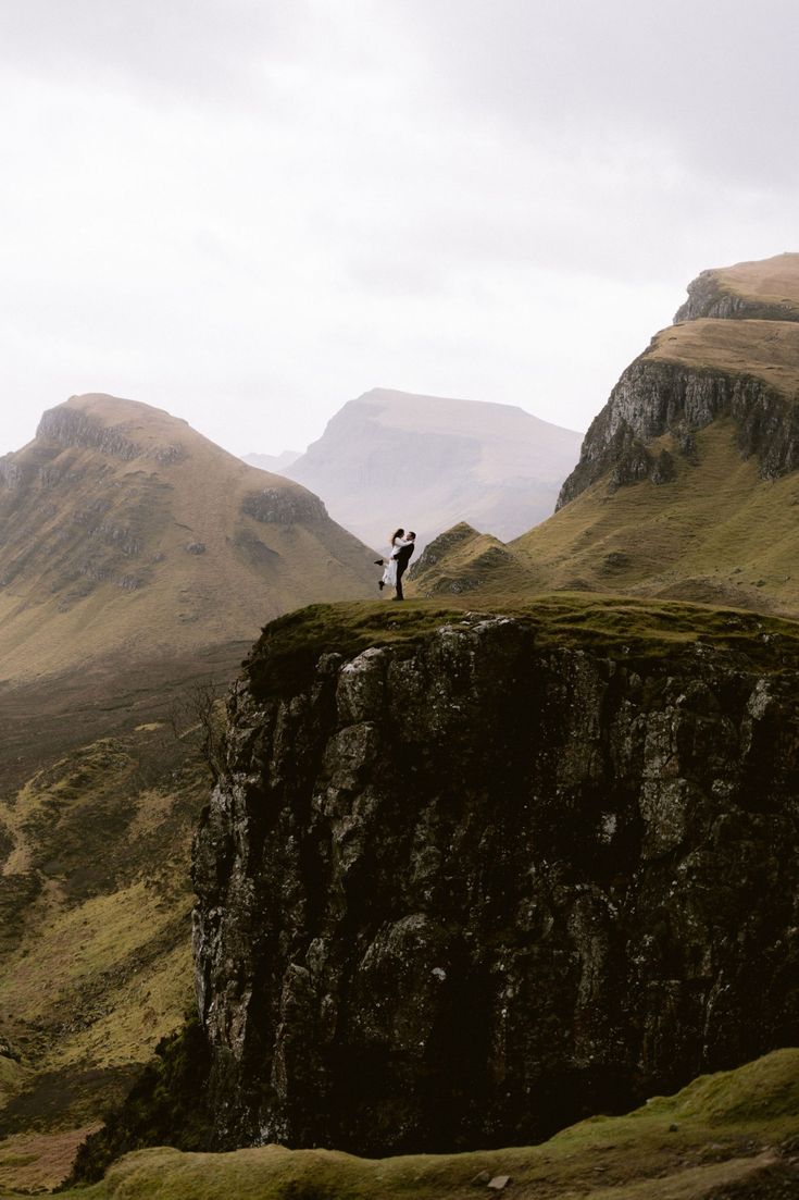 two people standing on the edge of a cliff