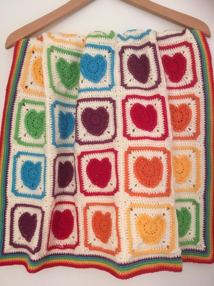 a crocheted blanket hanging on a wooden hanger