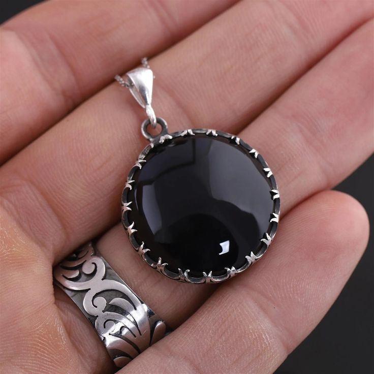 This sterling silver handmade pendant necklace features a stunning black onyx gemstone. The onyx adds a touch of elegance and sophistication to the necklace, making it the perfect accessory for any occasion. The pendant hangs from a sterling silver chain, which adds a touch of shine and sparkle to the necklace. The necklace is perfect for anyone looking for a stylish, timeless piece of jewelry that can be dressed up or down. Are you looking for a truly unique and special piece of jewelry? Look no further than handmade necklaces! Our Handmade necklaces are crafted by skilled artisans who put their time, passion, and creativity into each piece they make. Unlike mass-produced necklaces, handmade necklaces are one-of-a-kind and have a certain character and charm that cannot be replicated. Each Onyx Pendant Necklace With Polished Finish, Black Enamel Round Pendant Jewelry, Silver Obsidian Pendant Necklace, Round Obsidian Jewelry For Gift, Obsidian Round Jewelry For Gift, Black Round Pendant Jewelry, Obsidian Round Jewelry Gift, Silver Obsidian Gemstone Necklace, Black Agate Pendant Jewelry