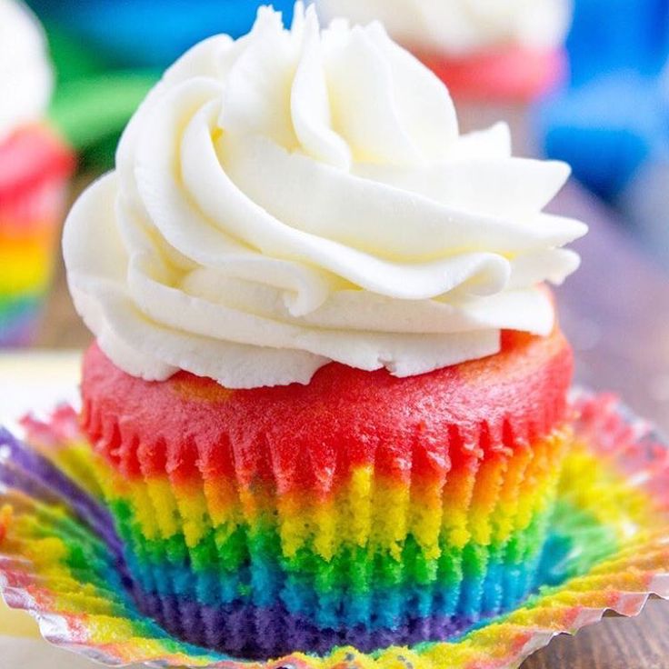 a cupcake with white frosting and rainbow decorations