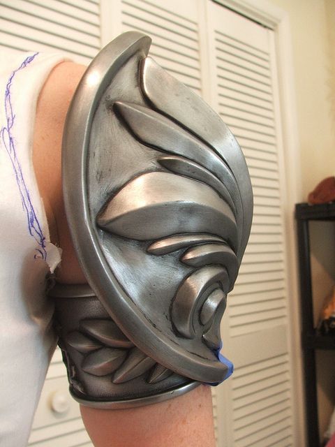 a person wearing a metal mask on their arm with one hand in the other's pocket