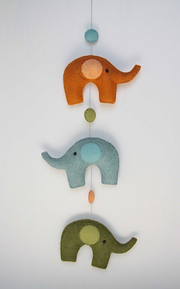 three felt elephants hanging from a string on a white wall in the shape of an elephant