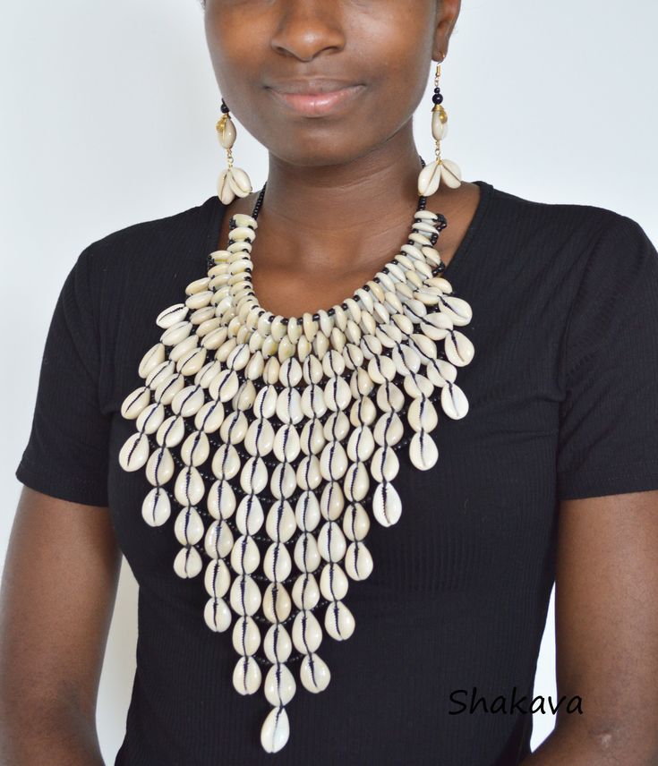 African inspired cowrie sea shell necklace bib design, unique and trendy. PRODUCT SPECIFICATIONS: Necklace length - 48.0 cm. Length downwards - 24.0 cm. Closure - brass hook Materials - beads, cowrie shells ADDITIONAL INFORMATION New and unworn: Yes Handmade in Kenya: Yes Other jewelry in my shop: https://www.etsy.com/shop/shakava Handmade Bib Necklaces For The Beach, Cowrie Necklace, African Beaded Necklace, Cowrie Shell Jewelry, Sea Shell Necklace, Cowrie Shell Necklace, African Accessories, Necklace African, Hook Necklace