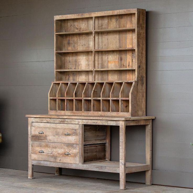 an old wooden desk with drawers and shelves on the top, in front of a gray wall