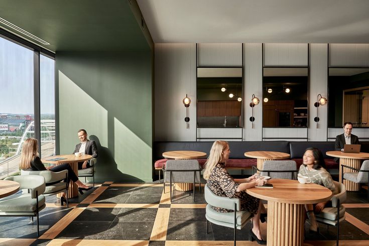 people sitting at tables in a restaurant with large windows