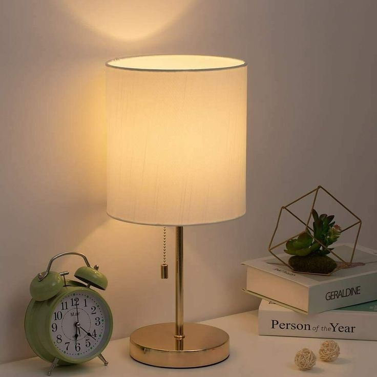 an alarm clock sitting on top of a table next to two books and a lamp