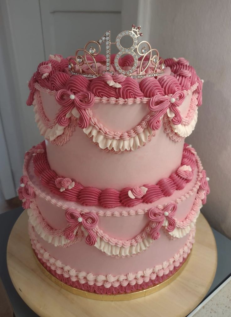 a three tiered cake with pink frosting and ruffles on the bottom