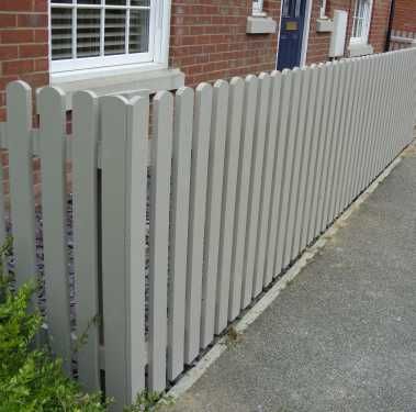 a white picket fence next to a brick building