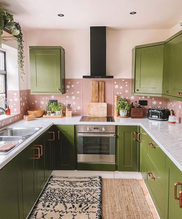 a kitchen with green cabinets and white counter tops, rug on the floor in front of the stove