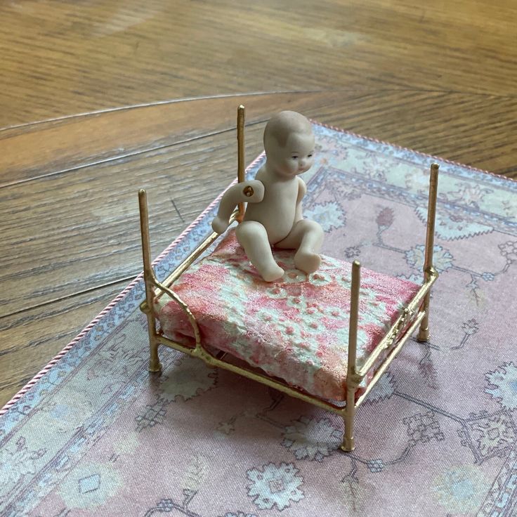 a small doll sitting on top of a miniature bed