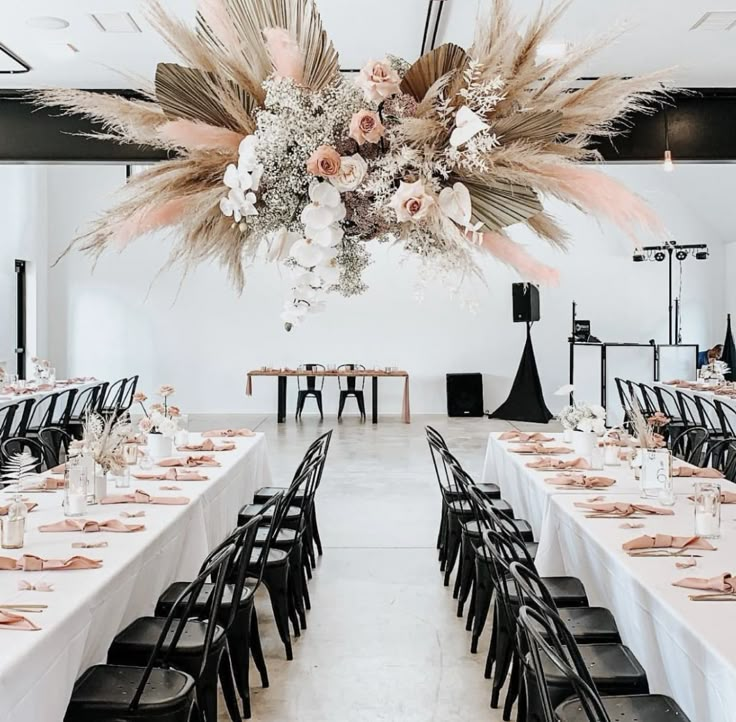 a room filled with lots of tables covered in white tablecloths and black chairs