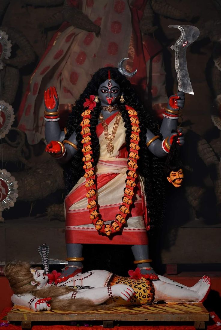 a statue of the hindu god and goddess in front of a wall with other decorations