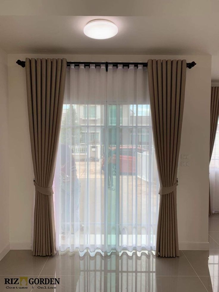 an empty living room with curtains on the windows