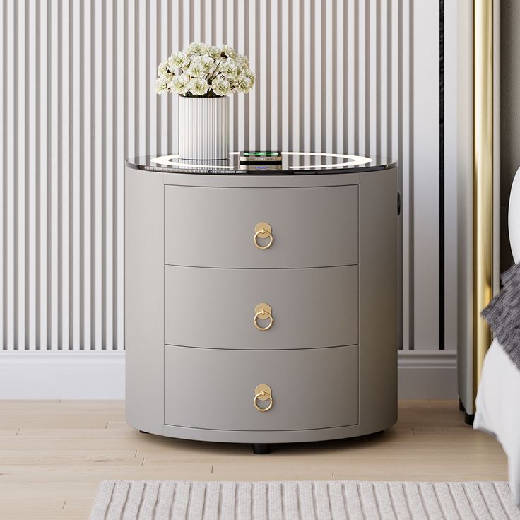 a round table with drawers and a vase on top in front of a striped wall