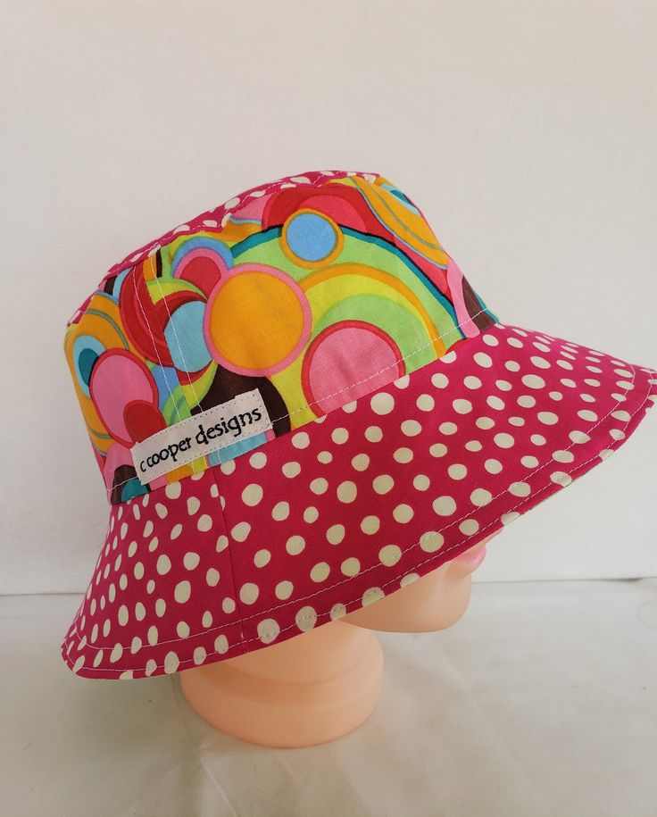 "Girls bucket hat is reversible, 2 hats in one! This hat is a must when ever you take the little one outside, gives protection from the sun on the face and head. A bright multi-color print with a pink brim on one side and a bright multi-color stripe with a green brim on the other. **Fits 3-5 years or approximately up to 21\" head circumference. *100% cotton fabrics *Machine wash-air dry *Completely reversible *CUSTOM ORDERS** Every item in the shop is one of a kind (OOAK) **If you see something Bucket Hat Designs, Bucket Hat Ideas, Lakers Hat, Toddler Sun Hat, Kids Sun Hat, Bucket Hat Design, Baby Washcloth, Hat Patterns To Sew, Painted Hats