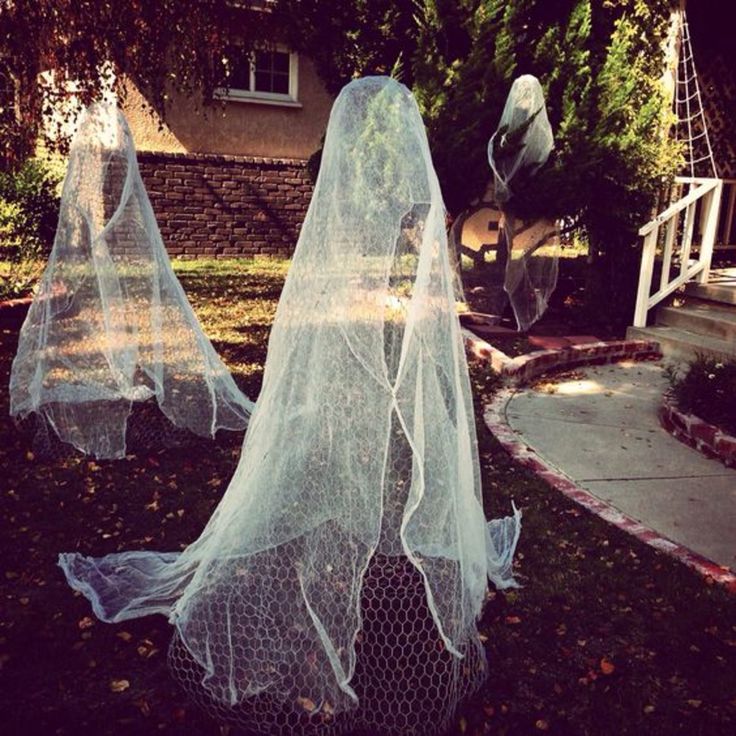 two plastic ghost statues in front of a house