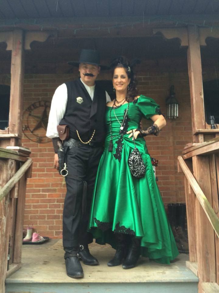 a man and woman dressed in costume standing on the steps of a building with their arms around each other