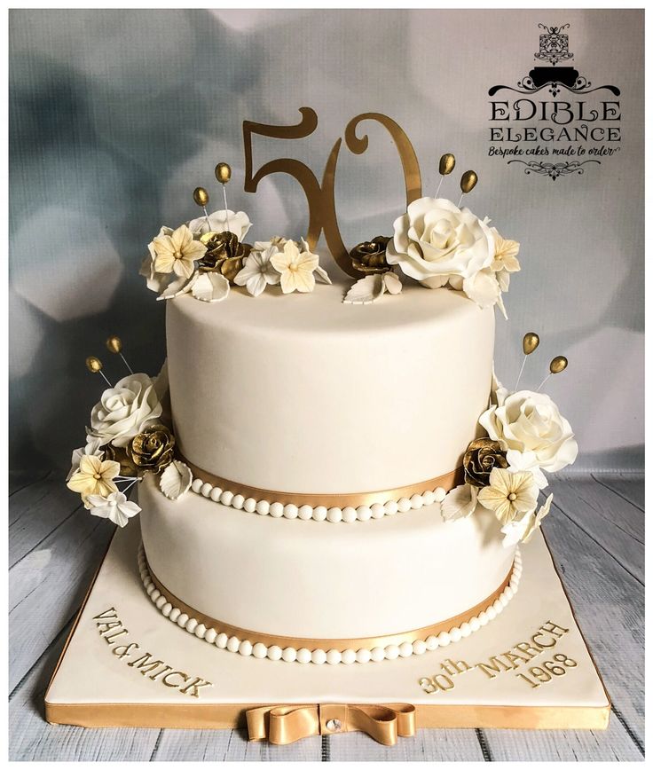 a 50th birthday cake with flowers and pearls on the top is decorated in gold, white and silver