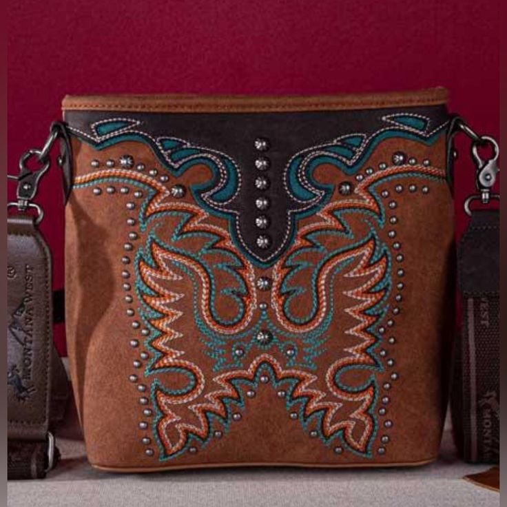 West Concealed Carry Crossbody Embroidered Collection Concealed Carry Crossbody 9.2" X 1.5" X 9.2" (Drop 24") Embroidered Boot Scroll On The Front Cut-Out Details Accented With Antique Silver Studs Dual Zippered Compartment And An Open Compartment In The Center Inside Zippered Compartments Have 2 Open Pockets And A Zippered Pocket A Zippered Pocket On The Back To Conceal The Handgun (7.5"X 5") An Open Pocket On The Back An Adjustable Crossbody Strap Item 2173-22-2