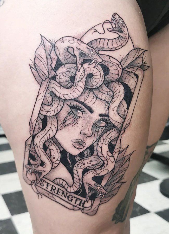 a woman's thigh with a snake tattoo on it and the words strength above her head