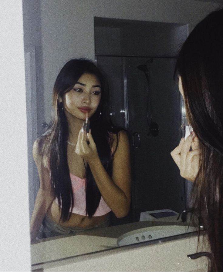 a woman is brushing her teeth in front of a mirror while looking at herself in the mirror