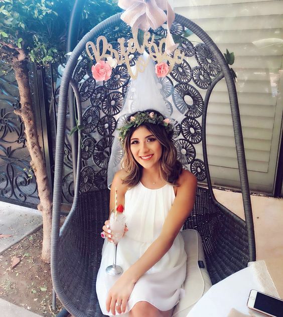 a woman sitting in a chair wearing a birthday hat and holding a wine glass with the word happy on it