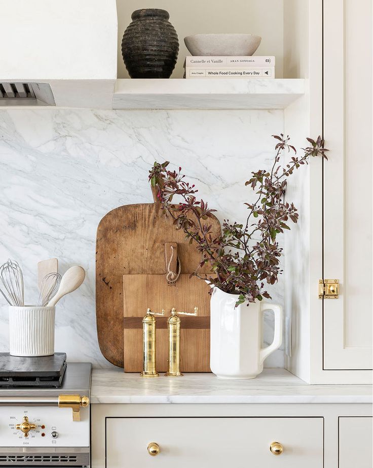 a cutting board and utensils on a counter in a white kitchen with gold handles