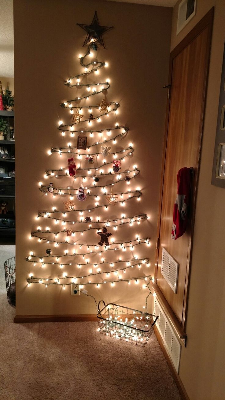 a christmas tree with lights on it in the corner of a living room, next to a basket