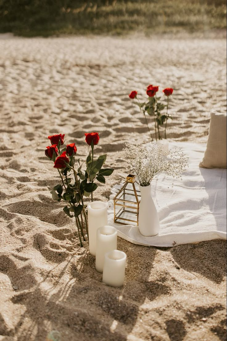 flowers and candles on the sand at the beach