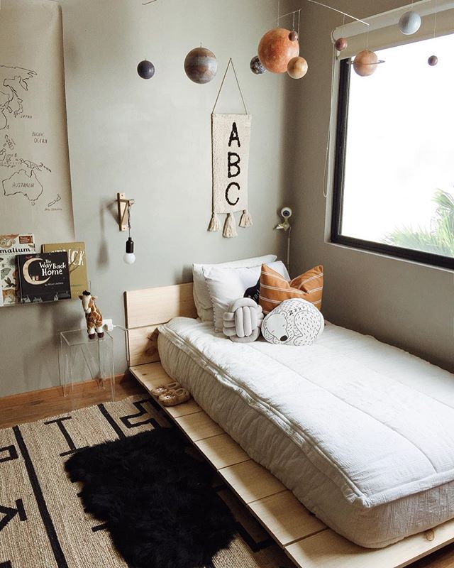 a room with a bed, rugs and pictures on the wall above it in front of a window