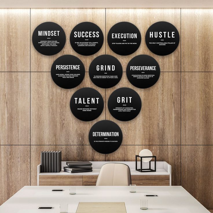 a white desk topped with lots of black circular wall art mounted to the side of a wooden wall