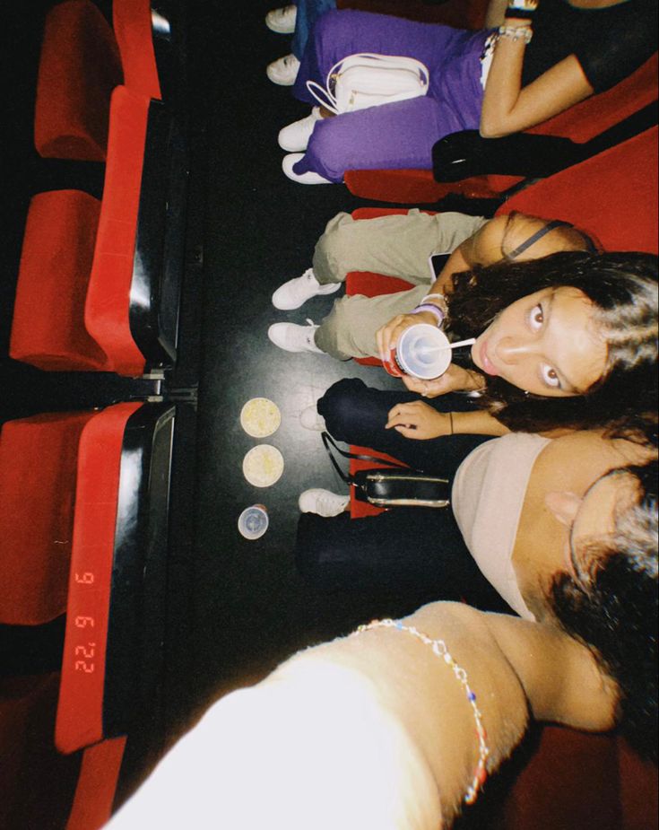 three women sitting on red seats in an auditorium